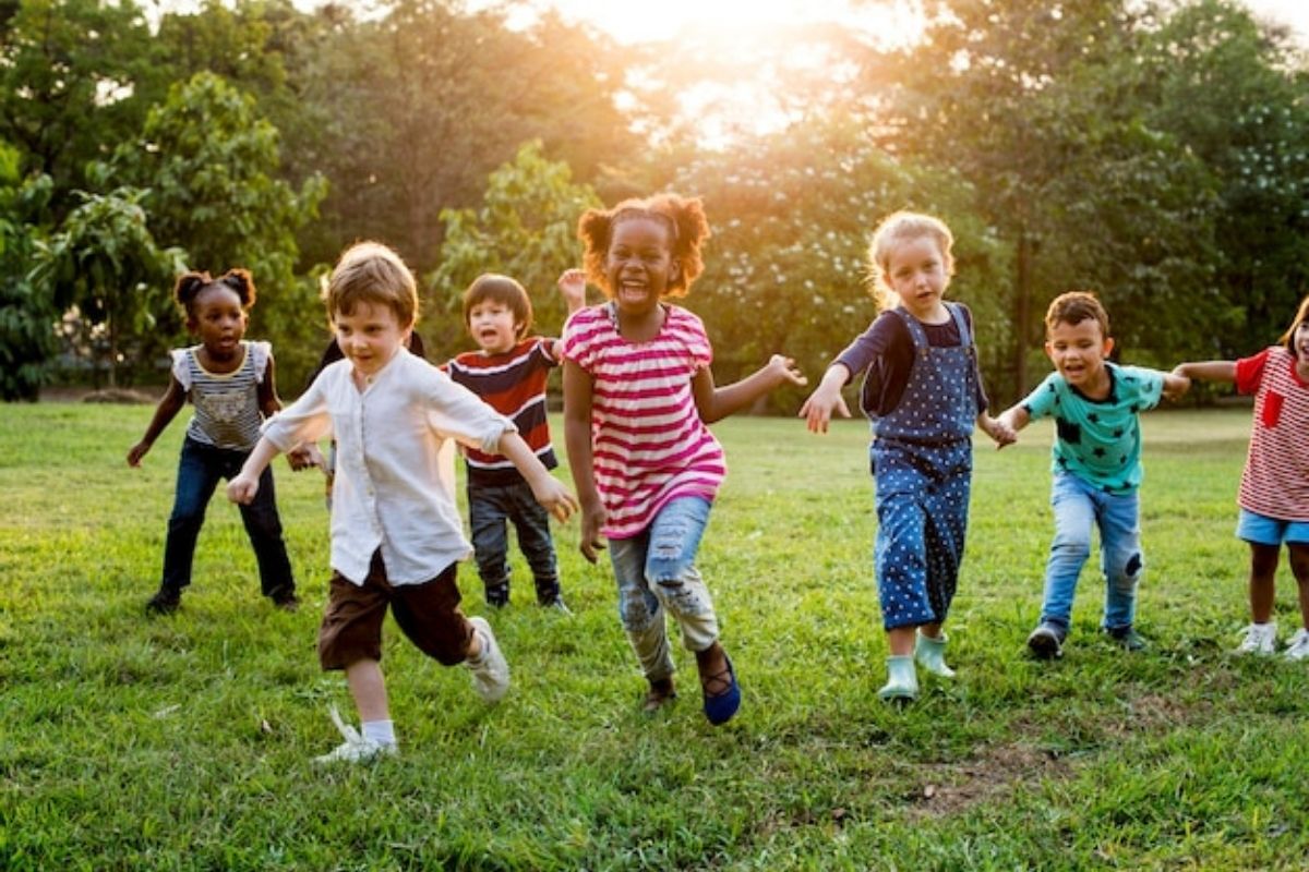 Bambini che giocano in un parco di Savona, circondati da alberi e aree verdi.